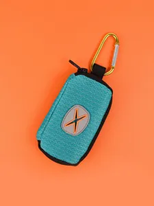 Teal pet waste bag dispenser detail view showing durable fabric and metal carabiner clip.