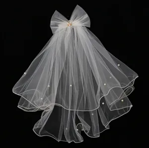 Detail shot of white multi-layer short bridal veil with bow and pearls for wedding photography.