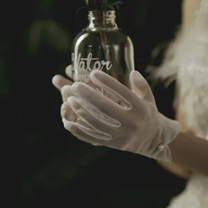 Elegant white sheer short bridal gloves with pearl detail for wedding photography style.