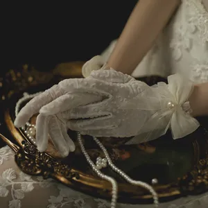 Vintage white lace mesh gloves with bow pearl details for bridal wedding photography