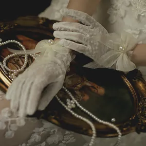 White lace mesh gloves featuring delicate bows and pearls for vintage wedding and party wear.