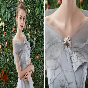 Exquisite crystal bow detail on elegant grey bridal shawl, sheer mesh evening wrap closeup.