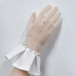 Primo piano dettagliato del guanto da sposa in rete bianca con perle delicate e polsino plissettato.