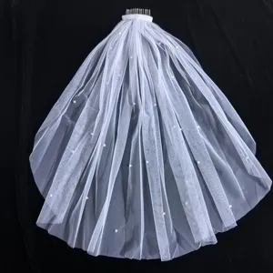 Gros plan du voile de mariée court à double couche orné de perles délicates et d'un peigne.