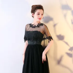 Détail de cape en dentelle noire élégante, avec broderie florale délicate et tissu transparent.