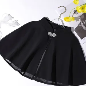 Close-up detail of the black chiffon cape featuring a sparkling rhinestone buckle.
