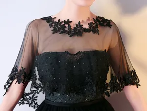 Vue détaillée d'un élégant châle cape en dentelle noire avec de belles broderies fines.