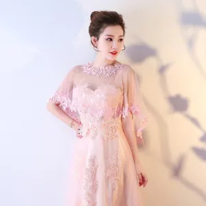 Détail de la cape de mariée élégante en dentelle rose avec tulle transparent et broderie florale.