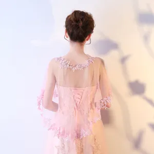 Détail de la cape de mariée rose délicate avec broderie florale complexe et tulle transparent.