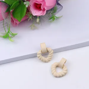 Detail shot of chic beige twisted heart earrings, showcasing textured acrylic craftsmanship.