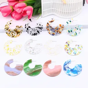Detailed view of colorful acrylic C-shaped geometric earrings with sparkling glitter and marbled patterns.