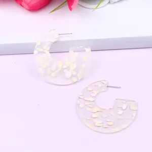 Transparent C-shaped acrylic earrings with sparkling glitter flakes, minimalist geometric design.