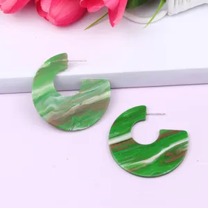 Green marbled acrylic C-shaped hoop earrings detail shot, geometric resin fashion jewelry.