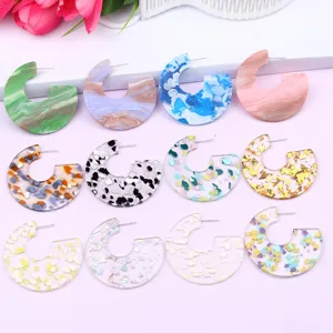 Colorful acrylic C-shaped geometric stud earrings with glitter and marble texture, detail view.