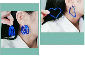 Gros plan detail des boucles d'oreilles creoles geometriques bleues portees a l'oreille.