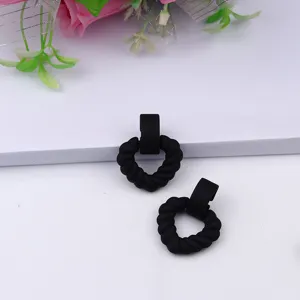 Detailed close-up view of black twisted heart stud earrings, matte acrylic geometric fashion jewelry.