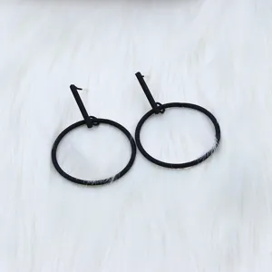 Close-up detail shot of minimalist black geometric drop earrings, modern style.