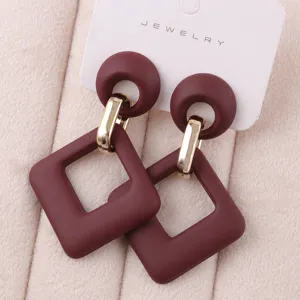 Pendientes colgantes de acrílico elegantes con diseño geométrico y detalles metálicos dorados.