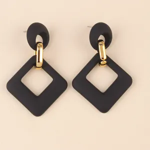 Primer plano detallado de elegantes aretes geométricos de acrílico negro y oro, chic.