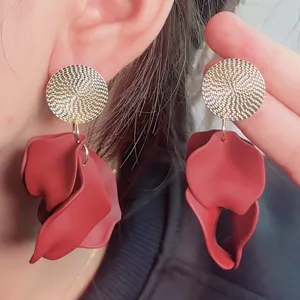 Detailed close-up of bohemian red petal earrings with gold textured disc studs for women.