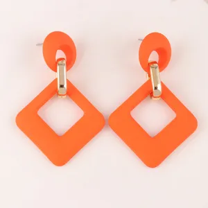 Pendientes geométricos de acrílico naranja con conector metálico dorado, diseño retro.