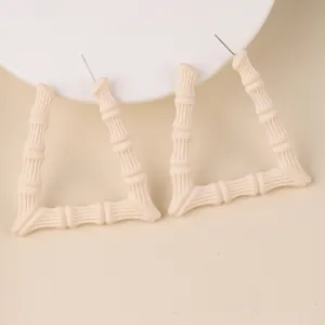 Detailaufnahme von schicken beige Acryl dreieckigen Bambus Ohrringen, minimalistisch.