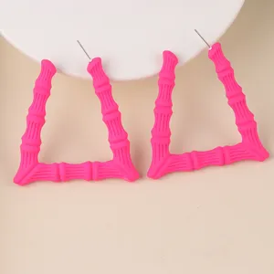 Nahaufnahme von leuchtend rosa dreieckigen Bambus-Ohrringen, modischem Acryl-Schmuck.