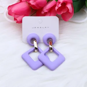 Pendientes colgantes geométricos de acrílico morado con conectores en tarjeta.