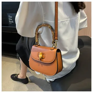 Sac bandoulière selle marron vintage avec poignée en bambou et serrure chic d'été.