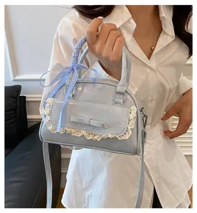 Detailed view of a light blue stylish handbag featuring cute lace trim and a blue ribbon.