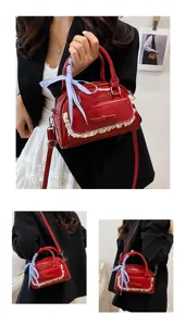 Detail shot of red patent leather handbag with delicate lace trim and blue checkered bow.