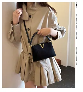 Black suede shoulder bag with gold V hardware and chic commuter style design for women.
