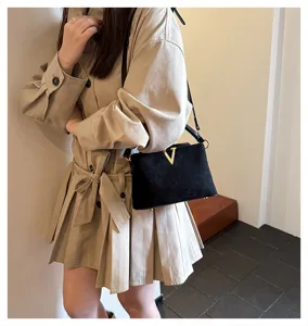 Detailed view of the black suede crossbody bag with gold V clasp, stylish commuter shoulder bag.