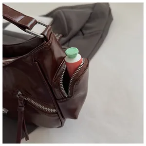Close-up detail of dark brown oil wax leather motorcycle shoulder bag with zipper pocket and metal.
