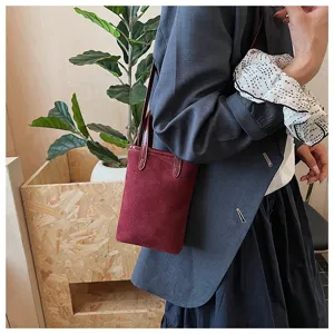 Vista dettagliata di una mini borsa da telefono in camoscio bordeaux con tracolla.