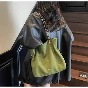 Green suede bucket shoulder bag with metallic chain strap and drawstring design, detailed look.