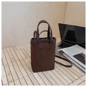 Dettaglio di mini borsa per telefono in camoscio marrone scuro, design tracolla.