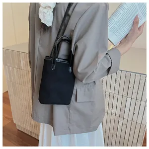 Vista dettagliata di una chic borsa a mano in tela nera con dettagli in pelle verniciata.