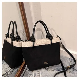 Detailansicht der schwarzen Wildleder-Lammfell-Eimer tasche mit Knotengriffen und Gurt.