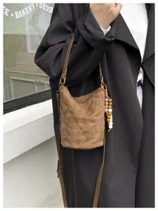 Primer plano del bolso saco acolchado de ante marrón con textura fina y abalorios de madera.