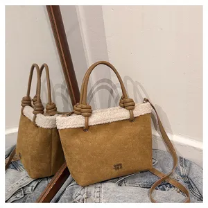 Nahaufnahme Detail einer braunen Wildlederhandtasche mit weißem Sherpa, Knoten und Schultergurt.