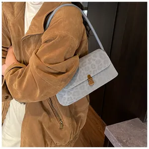 Detailaufnahme einer grauen Umhängetasche mit Leopardenmuster und Metallverschluss innen.