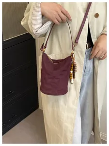 Vista detallada del bolso tipo cubo de ante acolchado con abalorio de cuentas y cremallera metal.