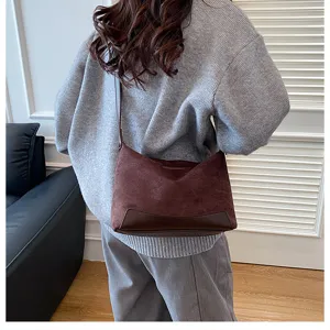 Detailansicht einer braunen Schultertasche aus Wildlederimitat an einem Model.