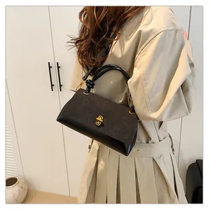Black suede panel shoulder bag detail showcasing the gold twist-lock and elegant top handle design.
