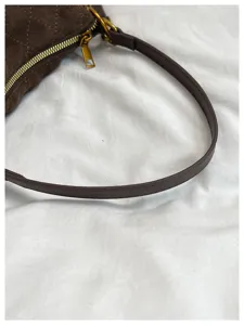 Detalle de bolso de hombro de ante acolchado marrón, elegante correa y diseño de cremallera.