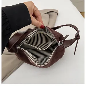 Braune Veloursleder Achseltasche Detail zeigt gestreiftes Innenfutter und Reißverschluss.