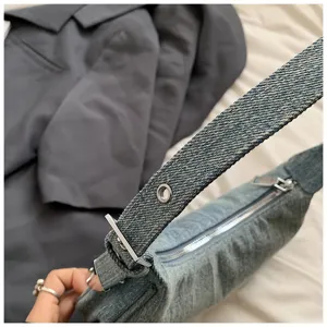 Denim hobo shoulder bag detail, zipper closure and metal ring strap accent closeup view.
