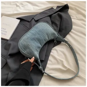 Close-up detail of stylish denim hobo underarm bag showcasing texture and metal zipper hardware.
