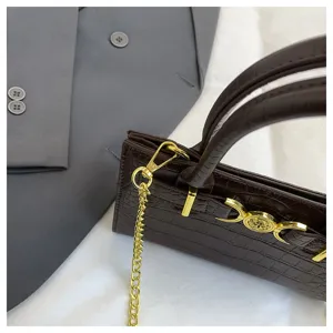 Detail van bruine handtas met krokodillenprint, gouden ketting en stijlvolle sluiting.